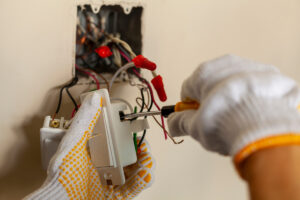 Two gloved hands repairing an electrical socket in an El Paso home.