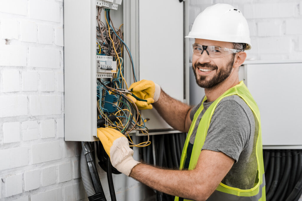 A smiling electrician making an electrical repair in El Paso.