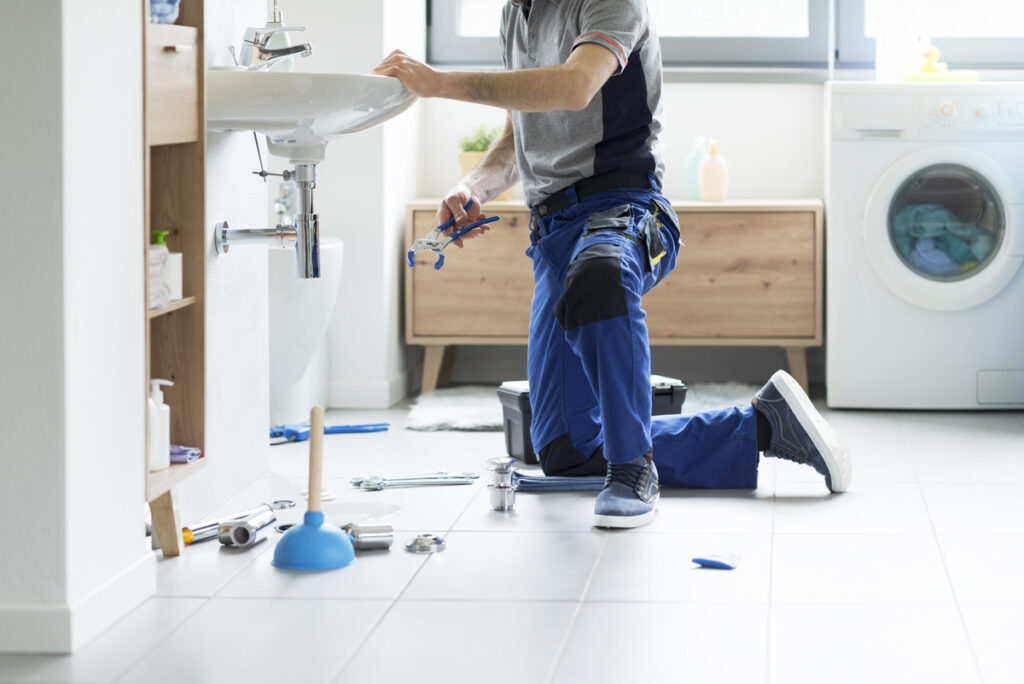 A plumber performing plumbing repair on a sink in an El Paso home.